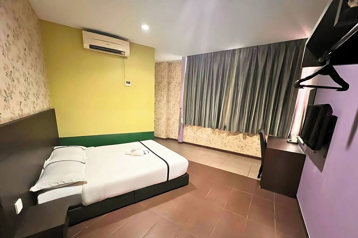 Ein Hotelzimmer mit Bett, Klimaanlage, Fernseher und Vorhang.
