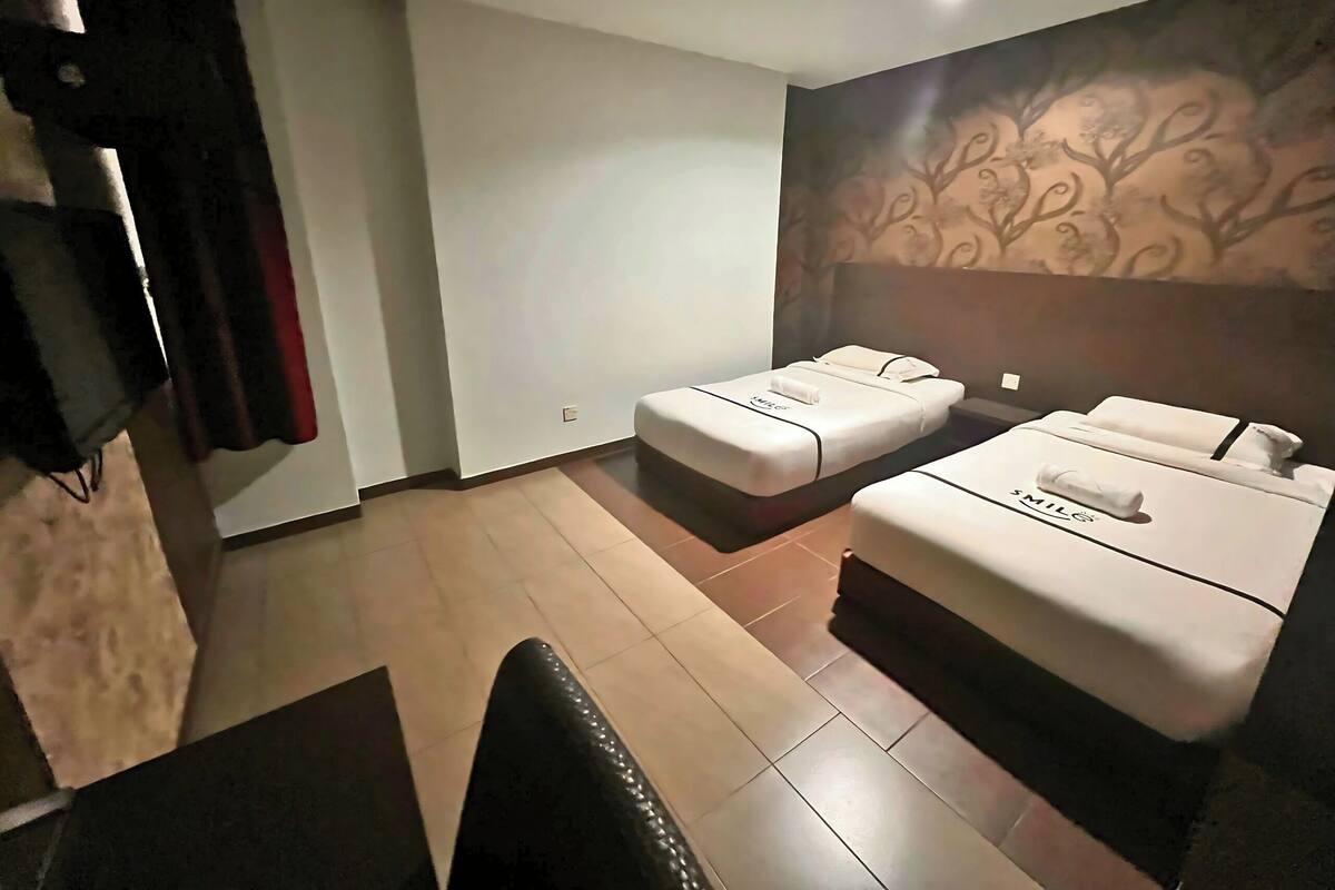 Ein Hotelzimmer mit zwei Betten, einem Fernseher und einer Wand mit Muster.