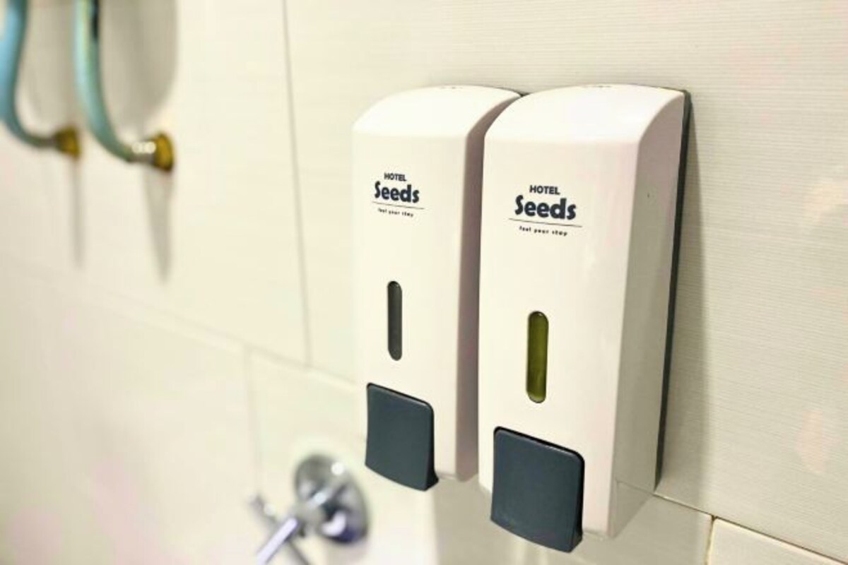 Een zeepdispenser bevestigd aan de muur met de aanduiding 'Hotel Seeds', in een hotel.
