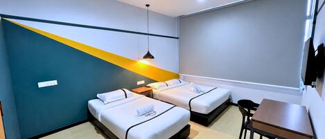A hotel room with two beds, a desk, a chair, and a modern pendant light.