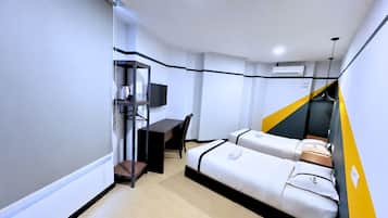 Une chambre d’hôtel de taille réduite, comprenant un lit, un bureau, une chaise, une télévision et une petite étagère.