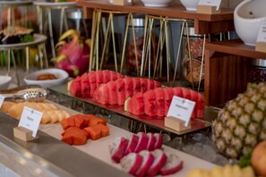 Un bufé con diversas frutas y verduras, incluyendo sandía, zanahorias y rábanos, presentado sobre una barra de vidrio.