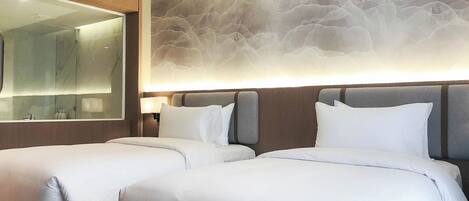 Habitación de hotel con dos camas, un espejo grande y un diseño de pared con textura.