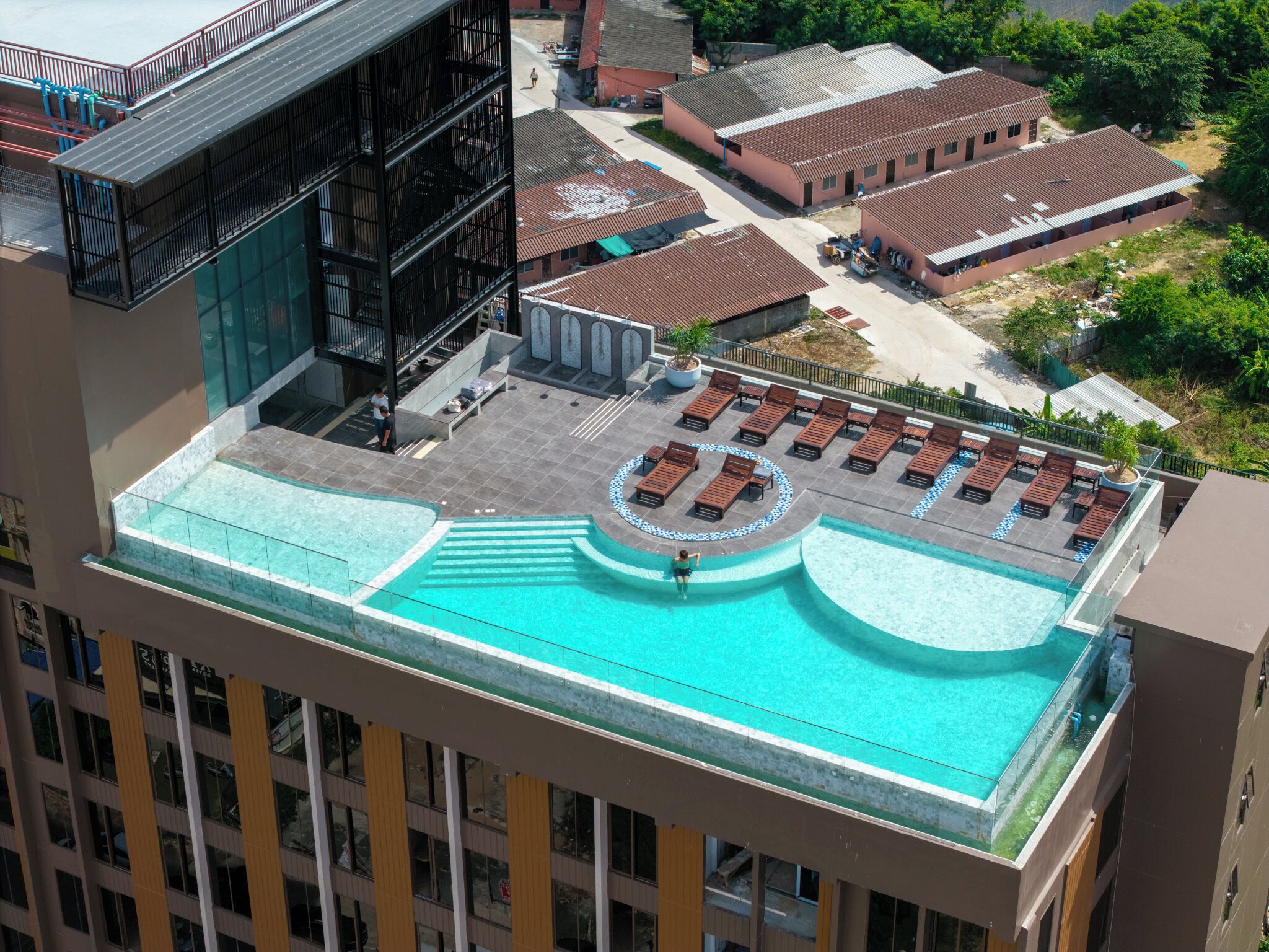 A rooftop pool with sun loungers and a circular seating area.
