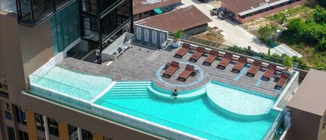 A rooftop pool with sun loungers and a circular seating area.