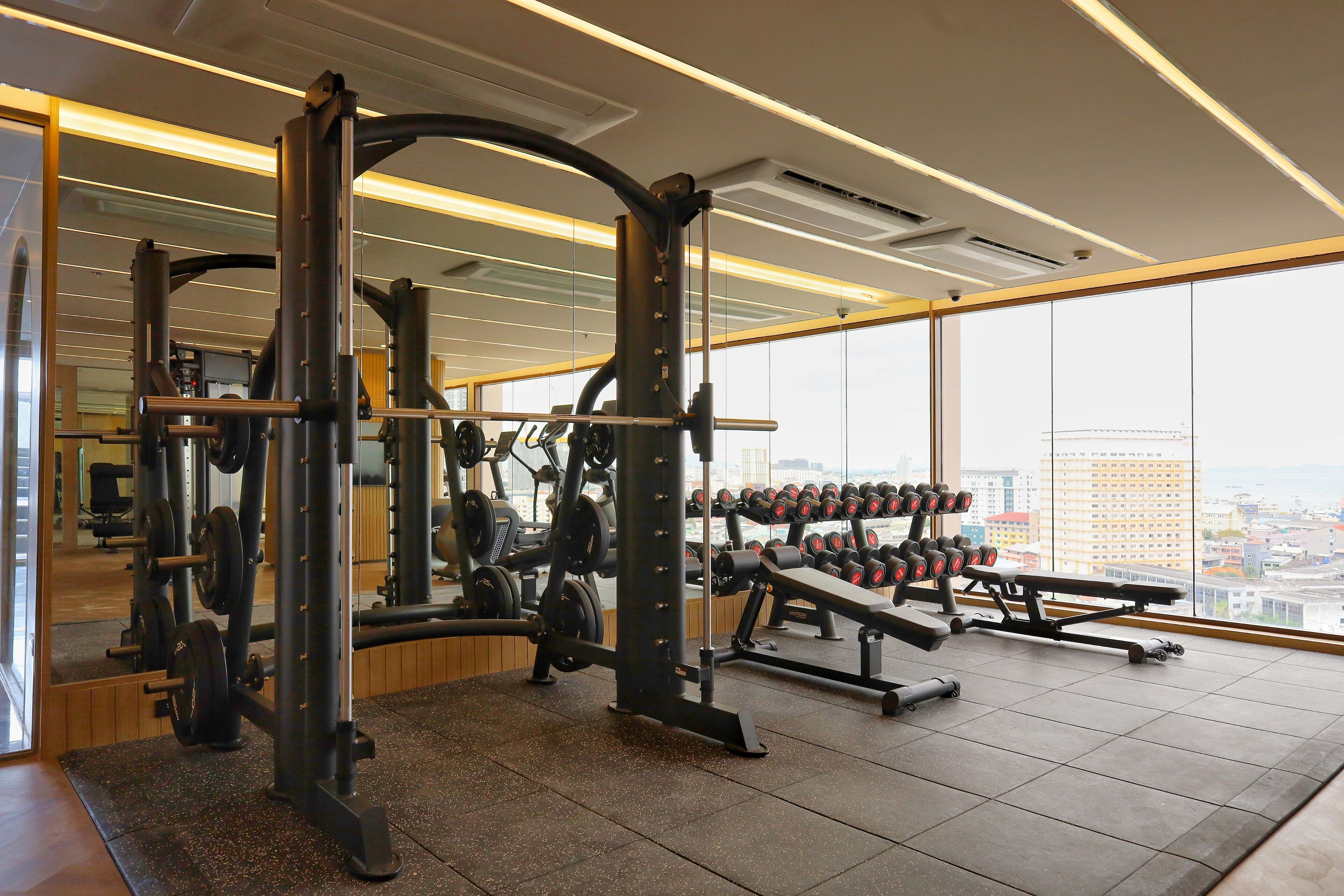 A gym with weightlifting equipment, a bench, and a rack of dumbbells.