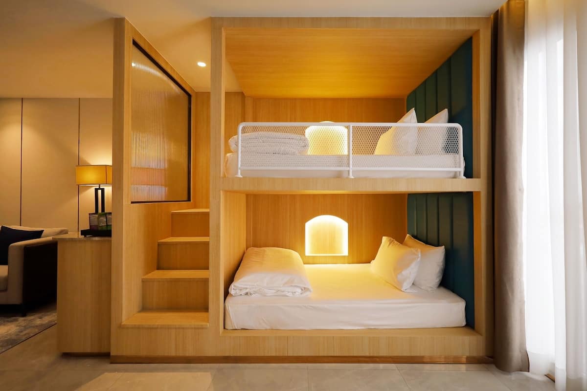 Een kleine, moderne hotelkamer met een stapelbed en een bureau.