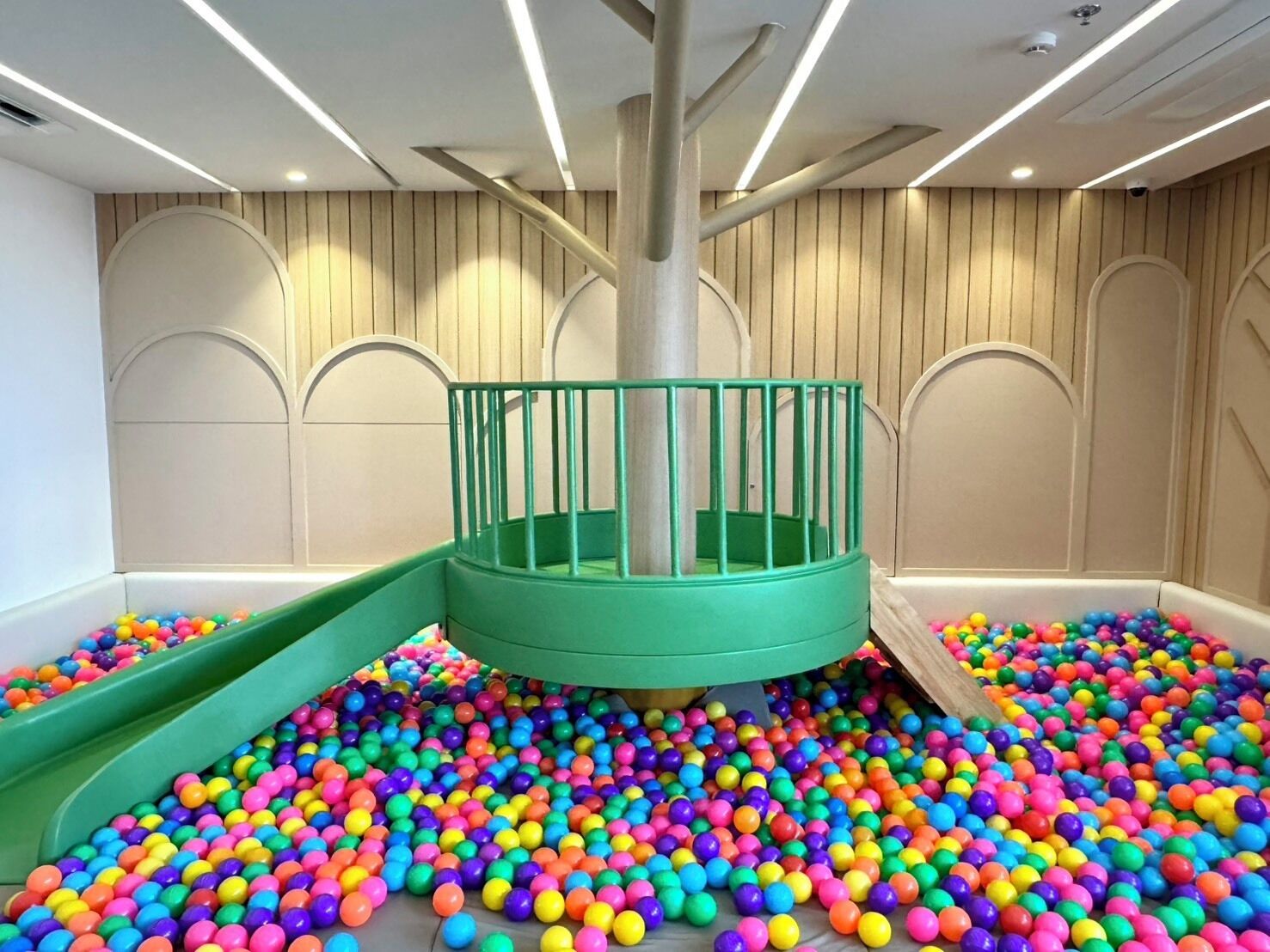 A play area with colorful plastic balls, a green slide, and a central pole.