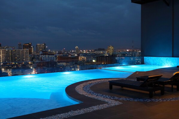 A rooftop infinity pool with a cityscape view, lounge chairs, and a pebble-lined edge. - Samsara Hotel Pattaya (Pattaya)
