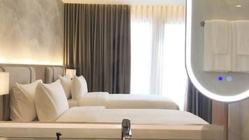 Una camera d'albergo con un letto, uno specchio grande, un lavandino e una finestra con tende.