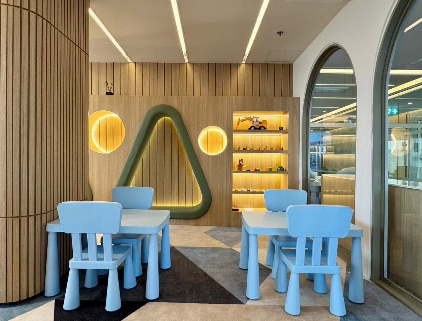 A modern interior with wooden panel walls, a unique geometric light fixture, and a display of toys.