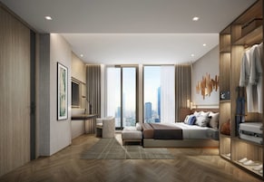 Quarto de hotel moderno com uma cama grande, área de estar e vista para o horizonte da cidade.