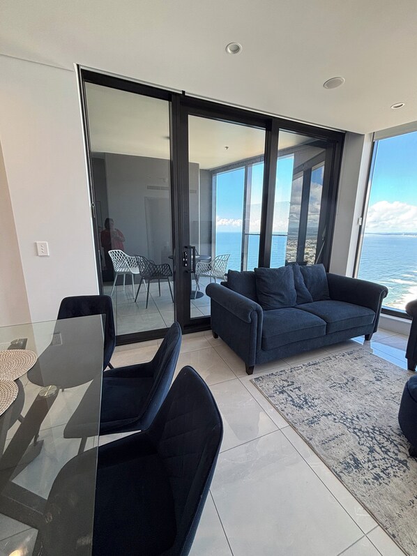 A modern living room with a glass door leading to a balcony with a city view.