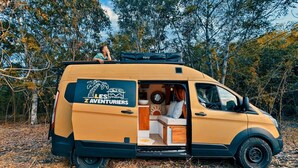 A van with a sleeping area, a kitchenette, and a logo on the side. - VAN Longani (Le Tampon)