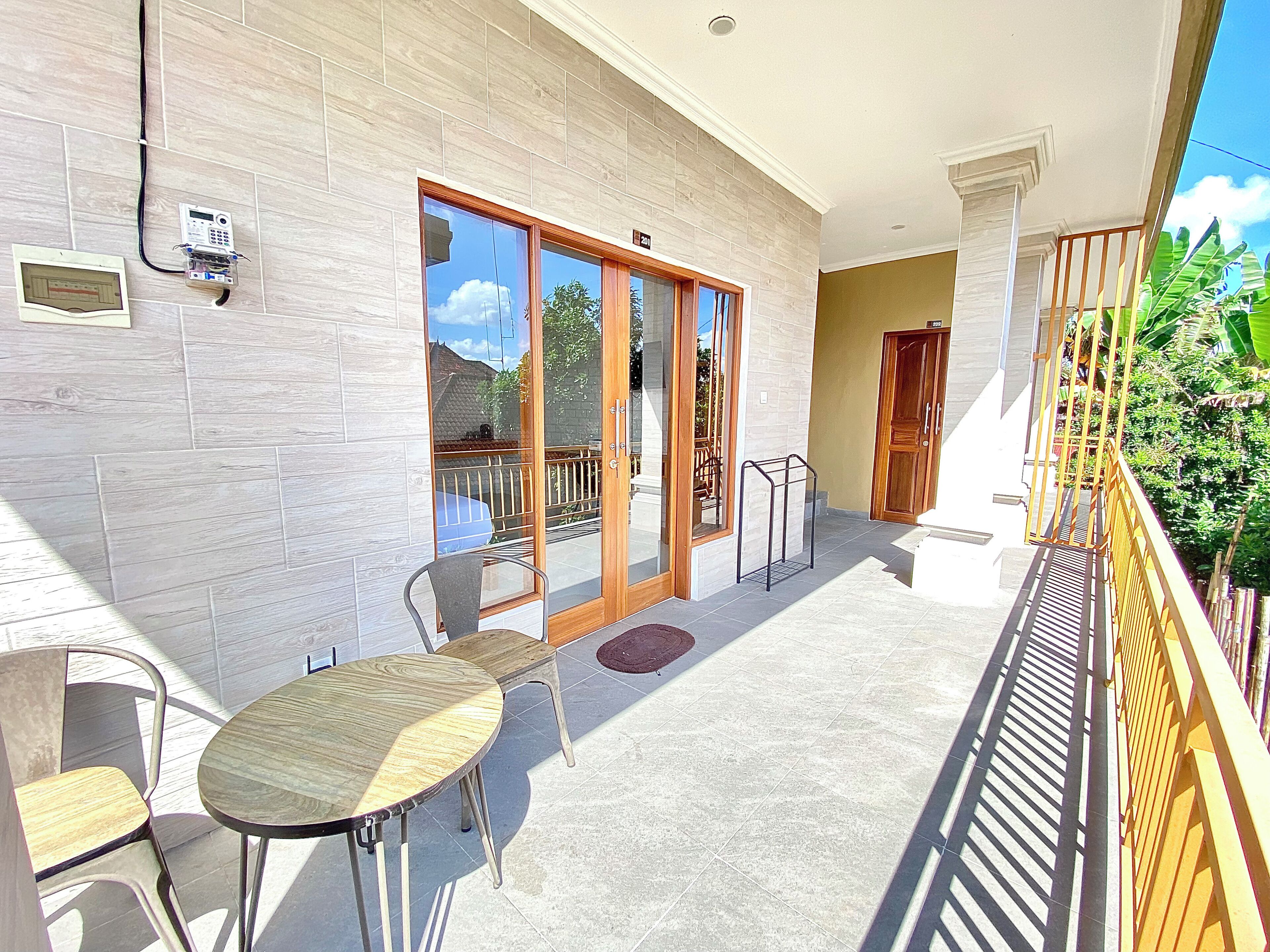 Uma varanda com mesa e cadeiras, uma porta de vidro deslizante e uma porta de madeira.