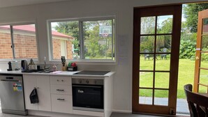 A kitchen with a window, a sink, a stove, and a dishwasher. - Garden View Entire Self Contained Guesthouse (Engadine)