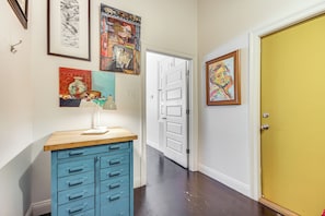 A hallway with a blue cabinet, a white door, and various framed artworks on the walls. - 10 Mi to Biloxi Beach & Casinos! Peaceful Retreat (Vancleave)