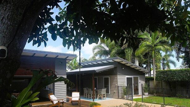 A modern house with a pool, outdoor seating, and lush greenery.