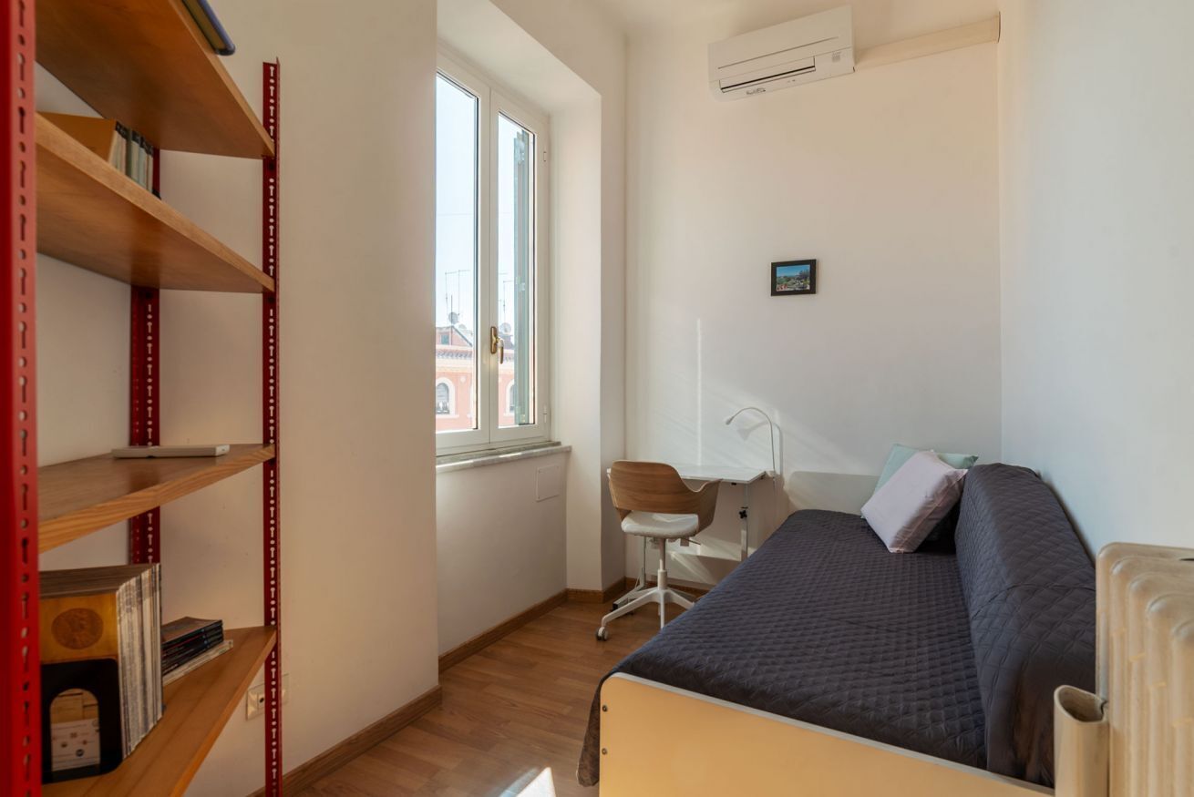 A bedroom with a bed, a desk, a chair, and a bookshelf.