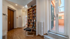 Une pièce avec un plancher en bois, une bibliothèque, une chaise, un radiateur et une porte donnant sur un espace extérieur.