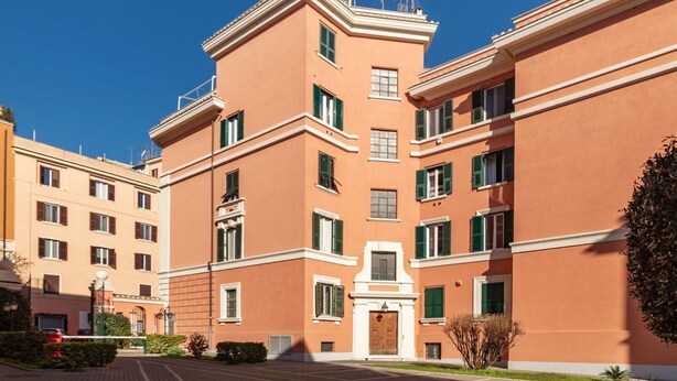 Un immeuble à plusieurs étages doté d’une entrée centrale, de nombreuses fenêtres et surplombant un ciel dégagé.