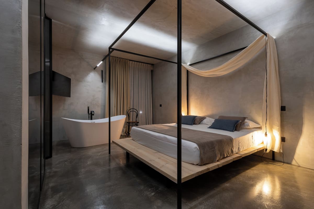 Un dormitorio moderno con cama con dosel, bañera independiente y diseño minimalista.
