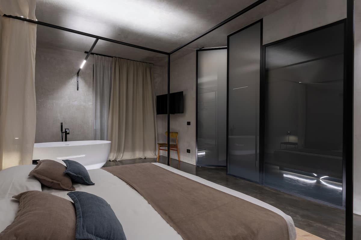 Un dormitorio moderno con una cama grande, una bañera y un ventanal corredero que da a una zona de ducha.