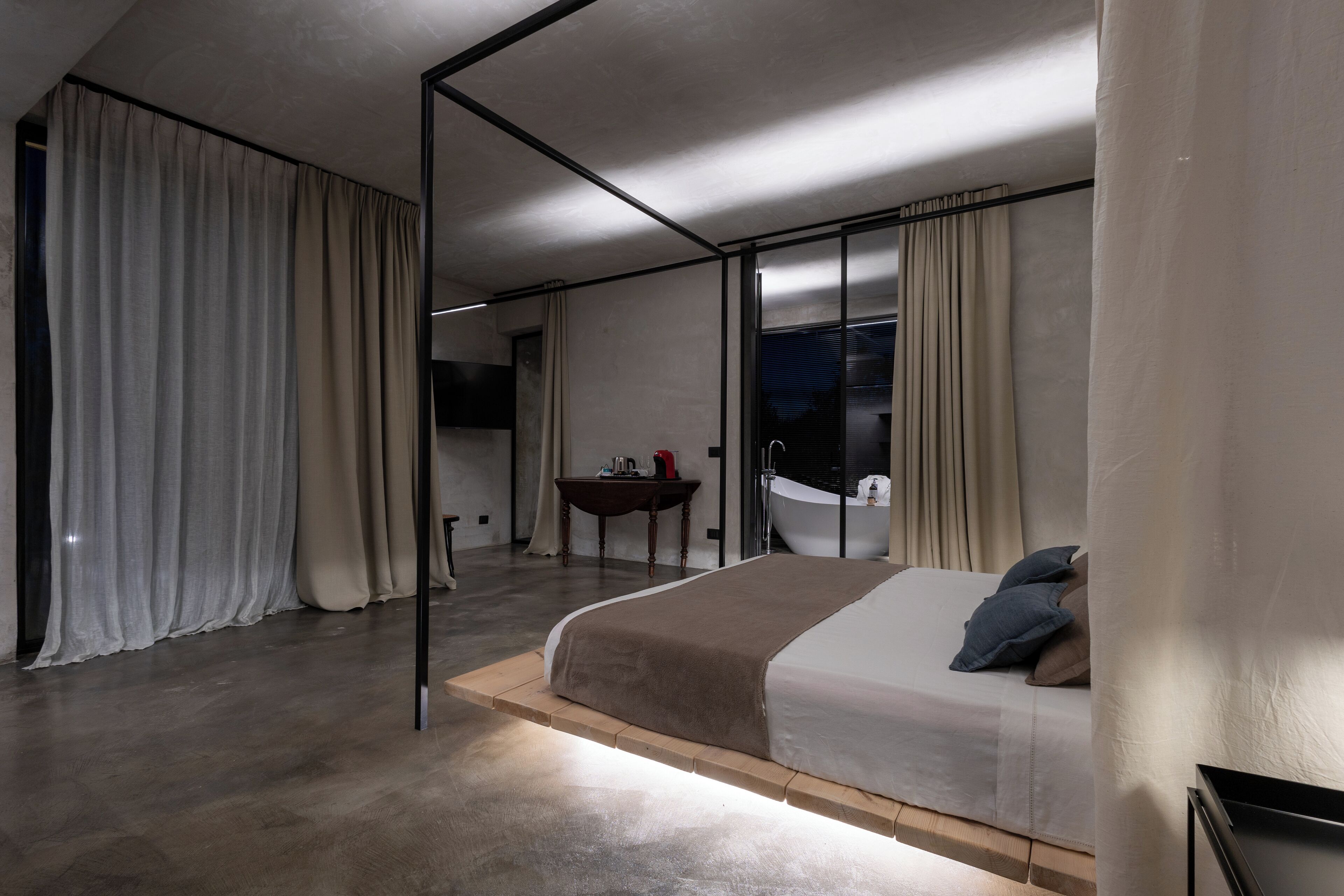 A modern bedroom with a large bed, a small table, and a bathtub.