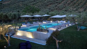 A modern outdoor pool area with multiple lounge chairs and umbrellas, surrounded by well-maintained grass and trees. - CASA PLENILIA (Pianella)