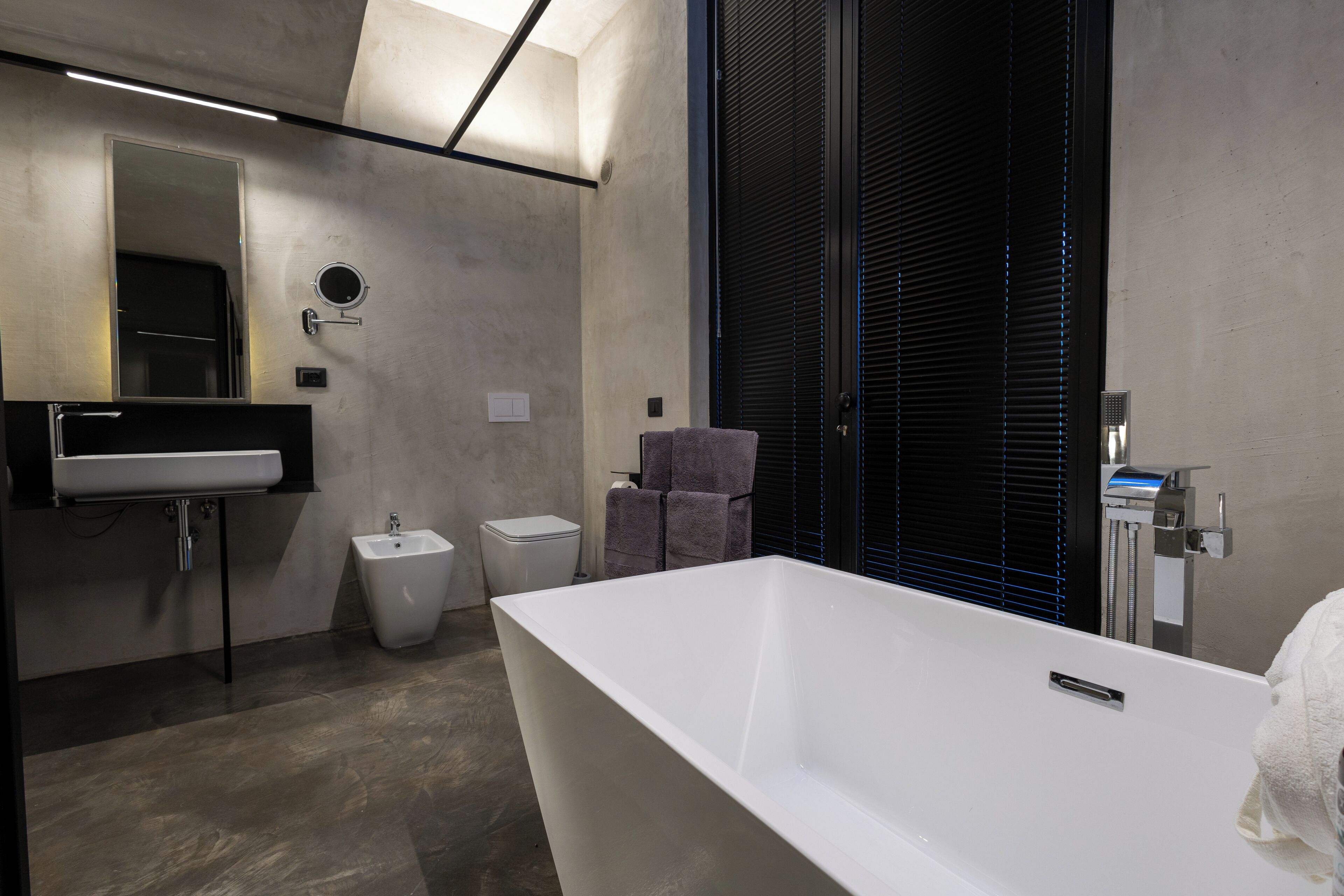 A modern bathroom with a large bathtub, a sink, a bidet, and a towel rack.