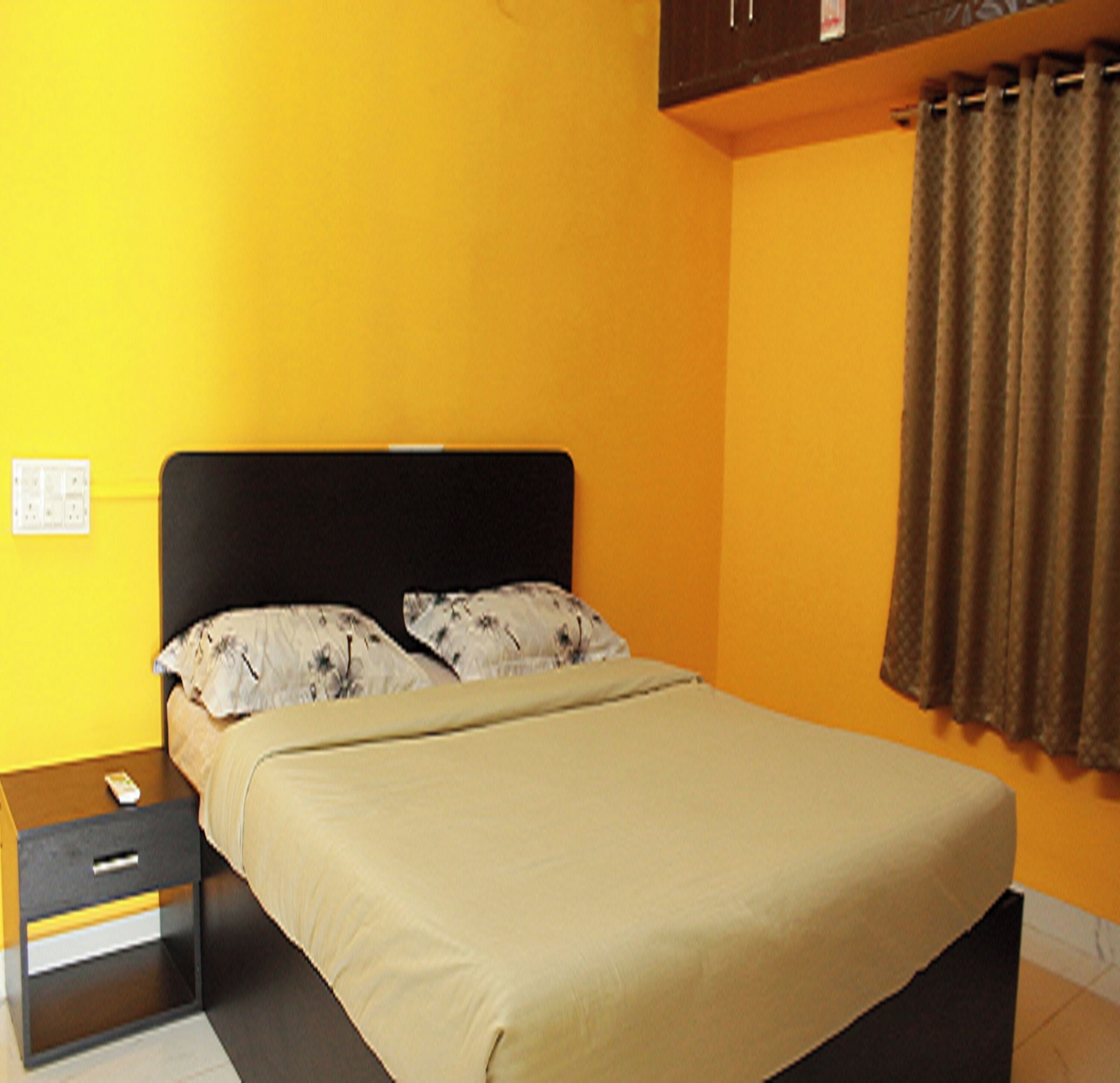 A bed with a black headboard in a room with yellow walls.