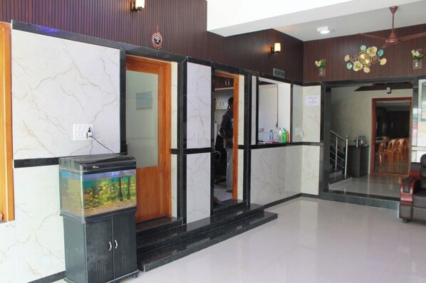 A reception area with a marble wall, a fish tank, and a staircase leading to a second floor. - Kalyan Residency (Madurai)
