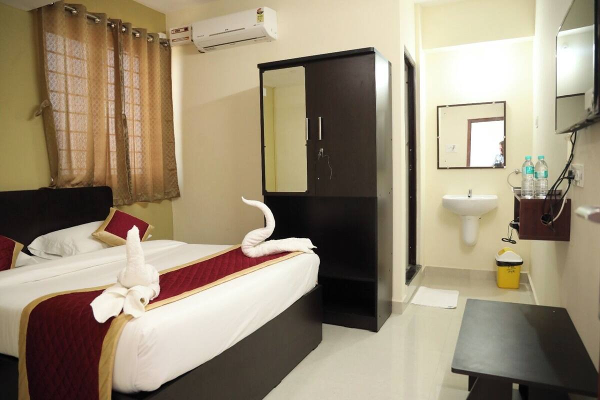 A hotel room with a bed, a wardrobe, a sink, and a small table.