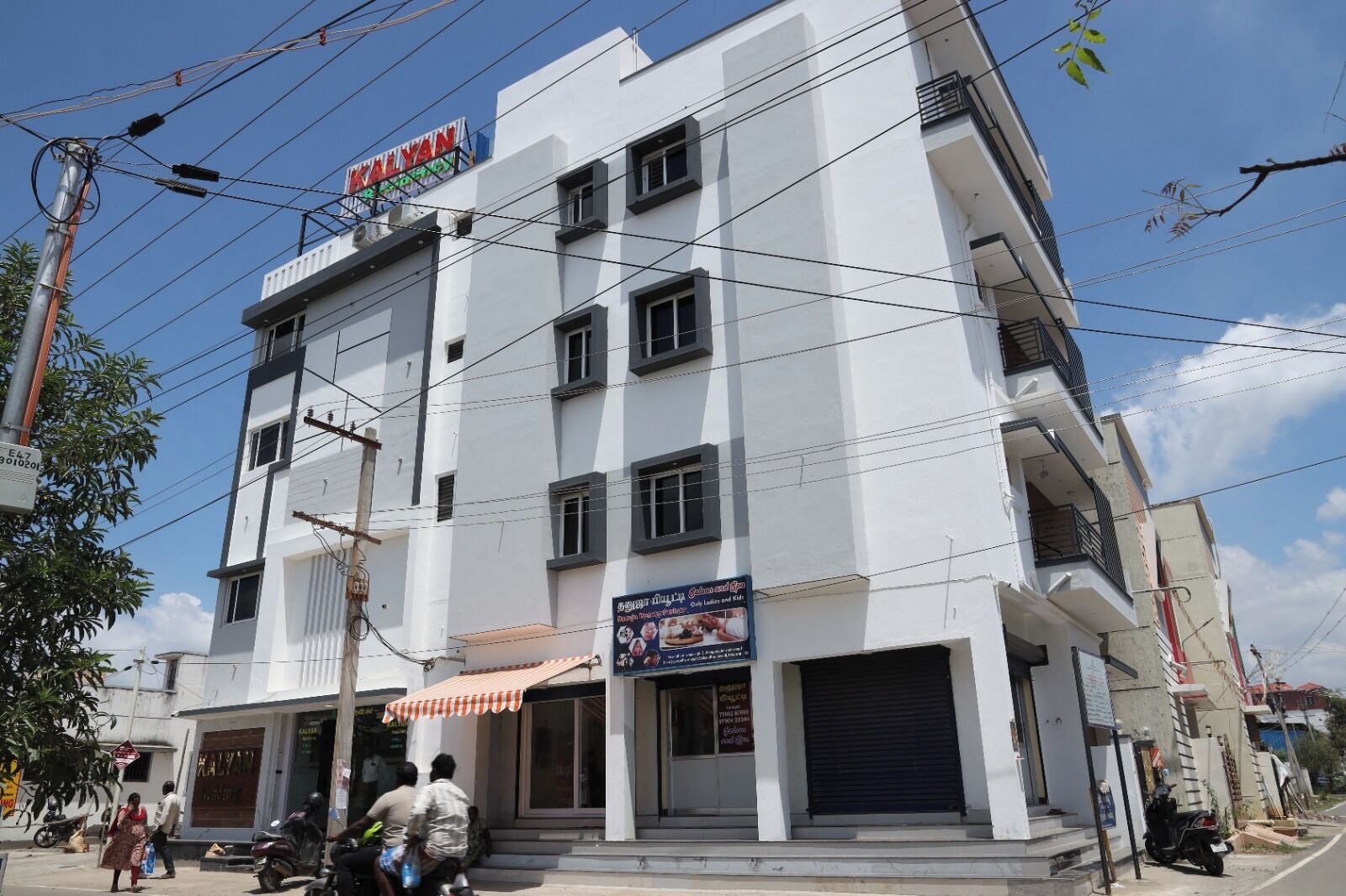 A multi-story building with a sign reading "KALYAN" at the top. There are multiple windows and balconies on the upper floors.