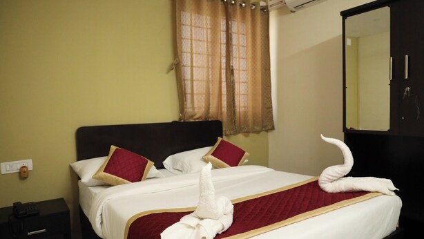 Een hotelkamer met een bed, nachtkastje, telefoon en spiegel.