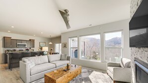 Ein modernes Wohnzimmer mit grauem Sofa, einem Holztisch und einem Kamin.