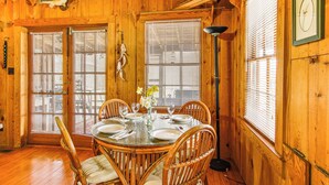 Comedor de madera con una mesa redonda dispuesta para seis personas, rodeada de sillas de mimbre.