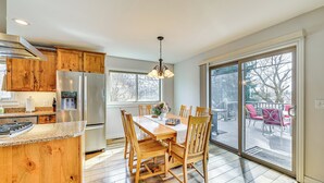 A kitchen with wooden cabinets, a stainless steel refrigerator, a granite countertop, and a dining area with a table and chairs. - Fish, Boat & Unwind: Spacious Missoula Gem w/ Deck (Missoula)