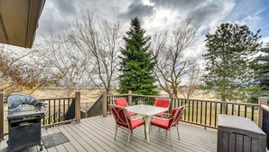 A deck with a barbecue grill, a table with red chairs, and a view of trees and mountains. - Fish, Boat & Unwind: Spacious Missoula Gem w/ Deck (Missoula)