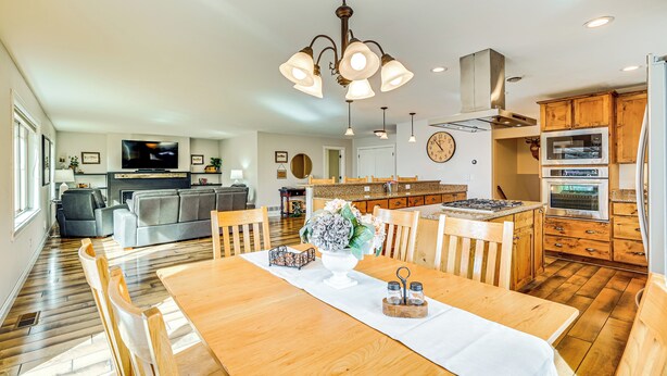 A modern kitchen with wooden cabinets, a built-in oven, and a dining area with a wooden table and chairs. - Fish, Boat & Unwind: Spacious Missoula Gem w/ Deck (Missoula)