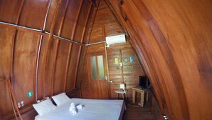Una habitación acogedora con paneles de madera, una cama, una mesita y un televisor.
