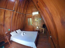 Una habitación acogedora con paneles de madera, una cama, una mesita y un televisor.