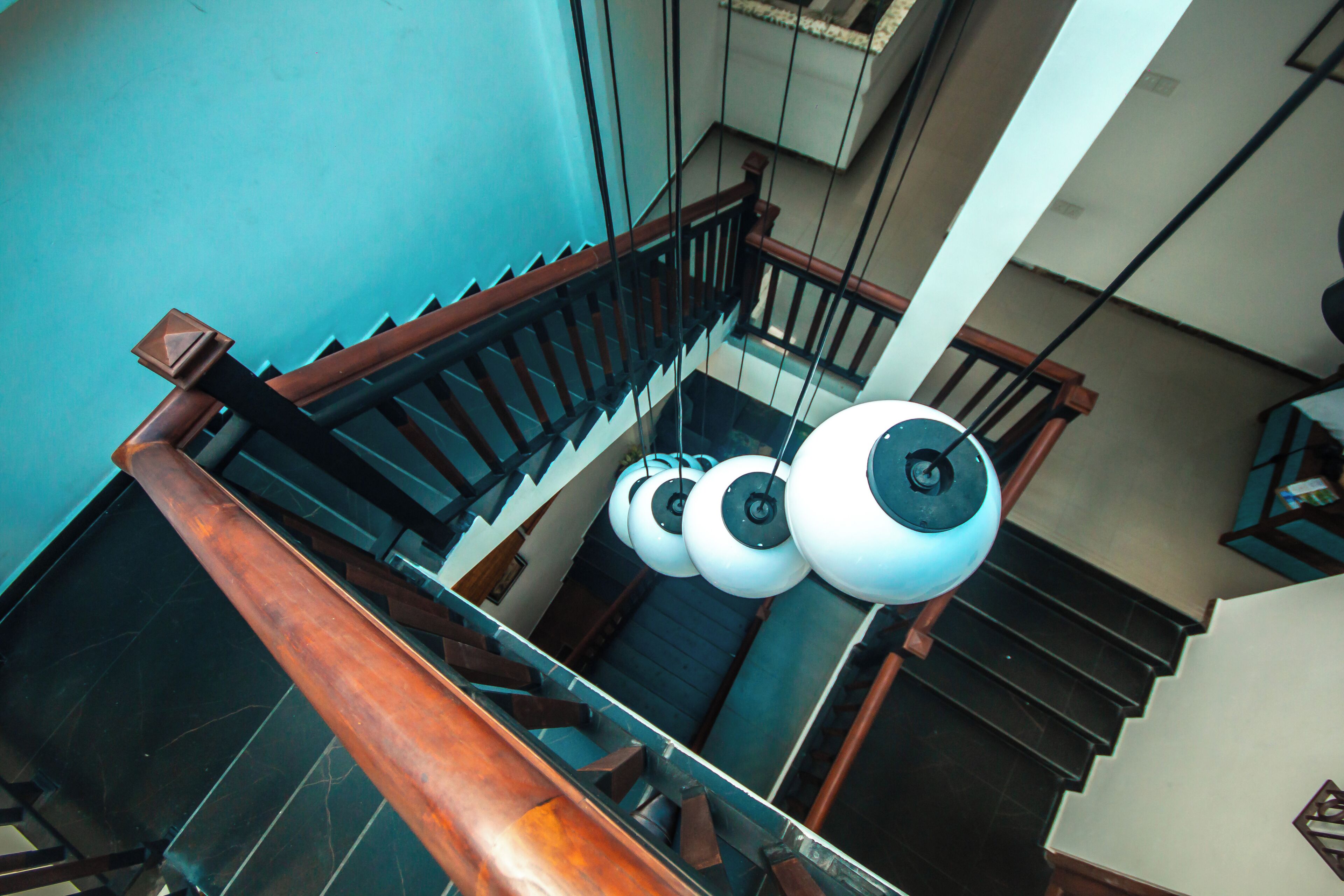 A multi-level interior with a staircase, metal railings, and hanging spherical light fixtures.