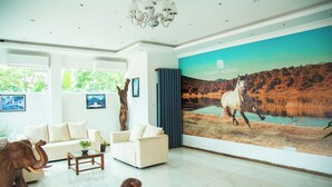 A spacious living room with a large mural of a horse, a white sofa, a coffee table, and elephant sculptures.