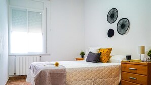 Una camera da letto con un letto, un comodino, una lampada e una finestra.