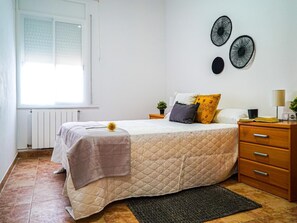 A bedroom with a bed, a nightstand, a lamp, and a window.
