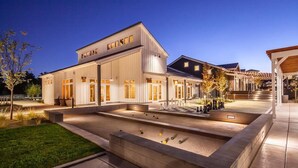 A modern building with a flat roof and large windows, surrounded by a well-lit courtyard with a pool and outdoor seating area. - South Reno 1BR · Near Reno Events, Pool & Gym (Reno)