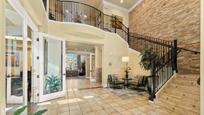 A spacious interior with a curved staircase, a dining area, and a view into another room. - South Reno 1BR · Hot Tub, Pool & Mini Golf (Reno)