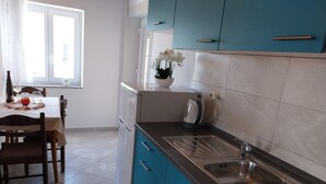 A modern kitchen with blue cabinets, a stainless steel sink, and a dining area with a table and chairs. - Metajna House With Pool And Sea View (Novalja)