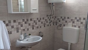A bathroom with a white sink, toilet, and a mirror above the sink. - Metajna House With Pool And Sea View (Novalja)